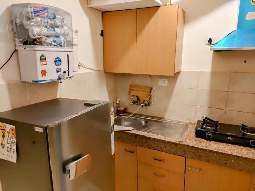 a kitchen with a stainless steel refrigerator and a sink at Entire Studio Apt/Suite near Mall/Metro/ExpoMart in Noida