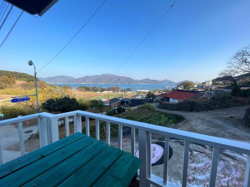 a wooden bench on a balcony with a view of the water at Artist and Flower Pension in Namhae