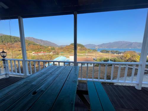 a wooden bench on a porch with a view of the ocean at Artist and Flower Pension in Namhae