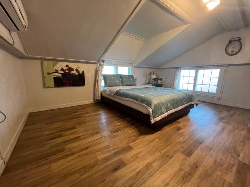 1 dormitorio con 1 cama y suelo de madera en Artist and Flower Pension, en Namhae