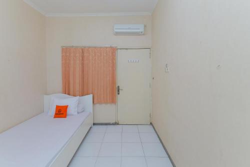 Habitación pequeña con cama con almohada naranja en Koolkost @ Siwalankerto en Surabaya