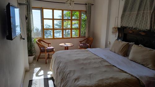 a bedroom with a bed and a window and a table at Mcleodganj Bed & Breakfast in McLeod Ganj