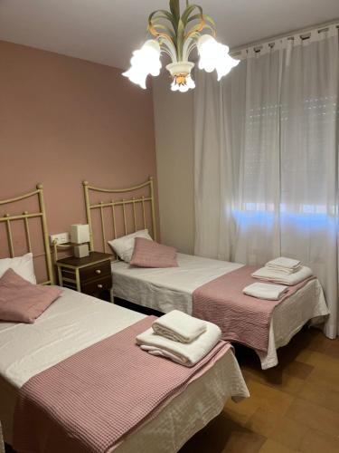 una camera da letto con due letti e un lampadario di EL RECREO a Mojados