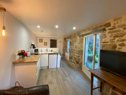 - une cuisine avec des appareils blancs et un mur en pierre dans l'établissement Studio cosy tout équipé en cœur de ville au calme, à Guingamp