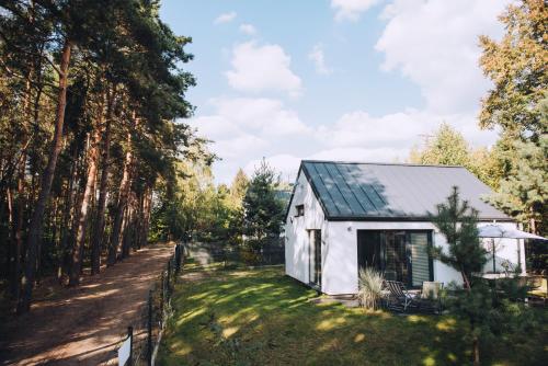 een wit huis met een tuin en bomen bij NAREV Domy Wakacyjne Pomiechówek Modlin Każdy Dom Ogrodzony in Pomiechówek