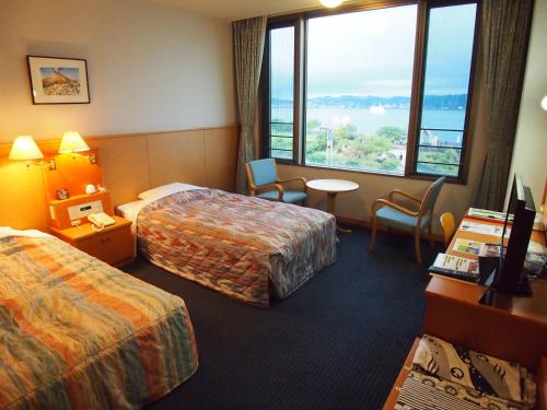 Sakurajimaにある国民宿舎レインボー桜島のベッド2台、テーブルと椅子が備わるホテルルームです。