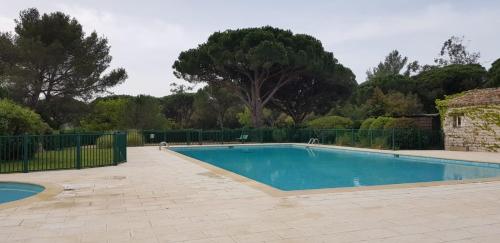 einen Pool in einem Garten mit einem Zaun und Bäumen in der Unterkunft Villa Domaine Font Mourrier in Cogolin