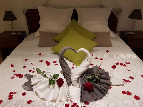 łóżko z czerwonymi różami i dwoma ręcznikami na nim w obiekcie LA TUILIÈRE : Détente Cocooning spa w mieście Courthézon