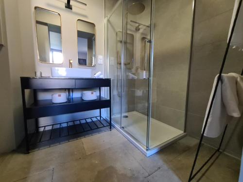 a bathroom with a glass shower and a sink at La Maison de Lyna - Suites de charme intra-muros avec parking & autonomie in Aigues-Mortes
