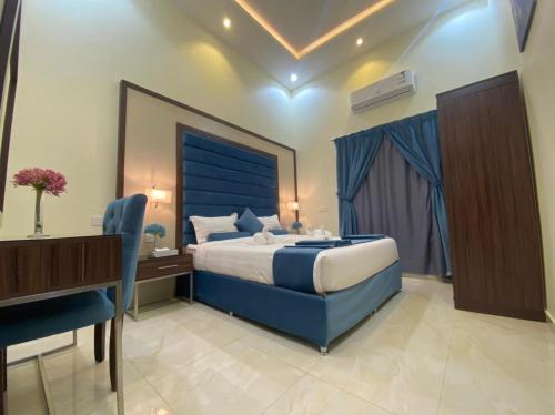 1 dormitorio con cama azul y escritorio en القصر المطار en Abha