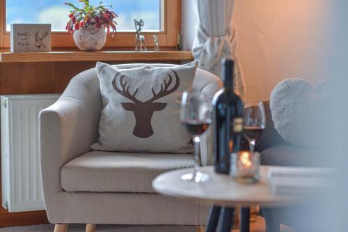 a living room with a chair with a deer pillow and wine glasses at Gästehaus Alpenruh in Fischen