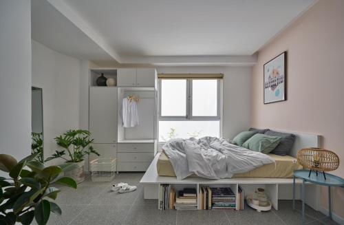 a white bedroom with a bed and a window at M Village Living Lê Văn Sỹ in Ho Chi Minh City