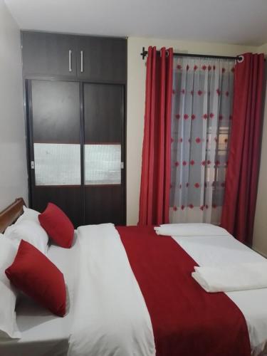 um quarto com 2 camas e cortinas vermelhas em City Haven Accommodation at Eagle court Apartment em Nairobi