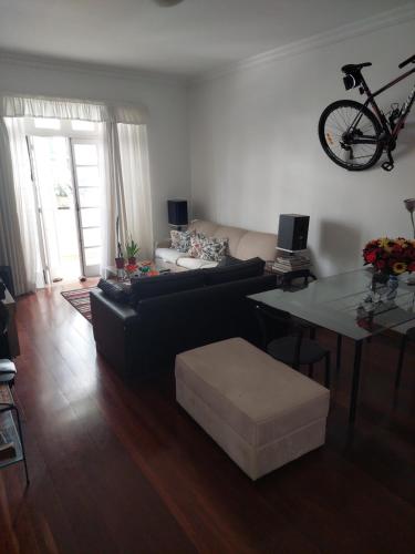 a living room with a couch and a table with a bike on the wall at Quartos em Laranjeiras in Rio de Janeiro