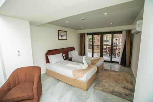 a bedroom with a bed and a couch and chairs at AIFU Hotel El Montazah Alexandria in Alexandria