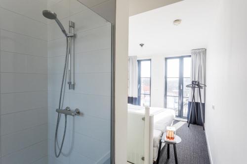La salle de bains est pourvue d'une douche avec une porte en verre. dans l'établissement Hello Zeeland - Appartement Markt 4 en 4A, à Domburg