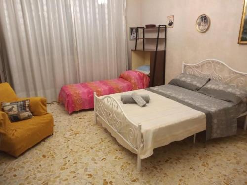 a bedroom with two beds and a chair at LG Appartamento Turistico Giarre in Giarre