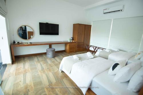a living room with two beds and a tv at River Arc Bolgoda Villa in Panadura