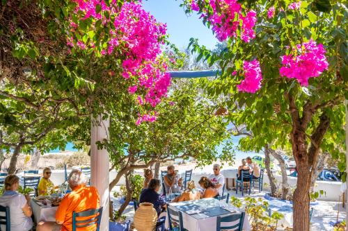 a group of people sitting at tables under trees with pink flowers at Poseidon Blue Gastronomy Hotel in Afiartis