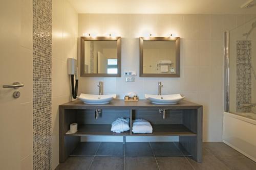 een badkamer met 2 wastafels en 2 spiegels bij Les Suites - Konine 4 - Hotel & Bar & Restaurant in Montceau-les-Mines