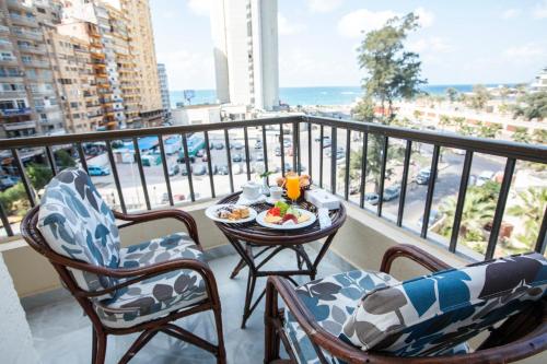 a balcony with a table with a plate of food on it at AIFU Hotel El Montazah Alexandria in Alexandria