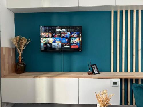 una televisione su una parete blu in una stanza di Chic and Elegant - Portes de Paris et la Défense a Bois-Colombes