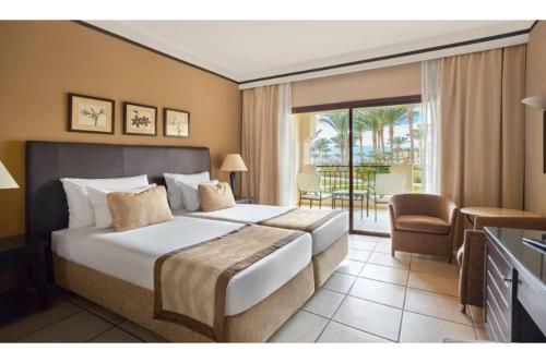 a hotel room with a large bed and a balcony at JAZ Lamaya Resort in Coraya Bay