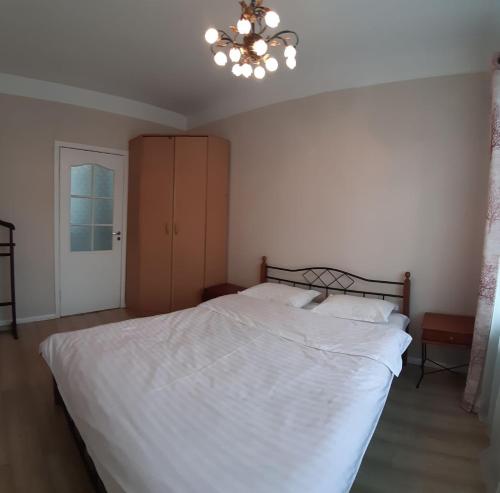 a bedroom with a large white bed and a chandelier at AURA on Erkindik boulevard in Bishkek