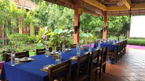 a long table with blue table cloths and wooden chairs at Memoria Palace & Resort in Pailin