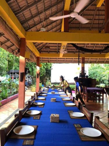 a long blue table with chairs and plates on it at Memoria Palace & Resort in Pailin
