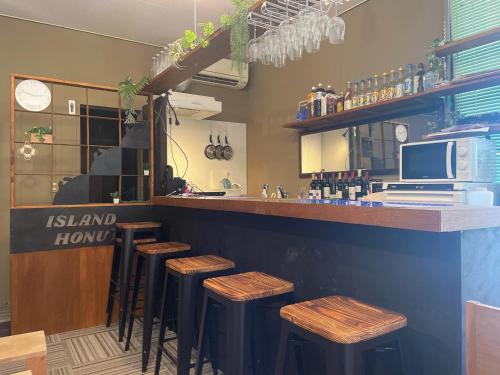 eine Bar mit Holzhockern in einem Restaurant in der Unterkunft IslandHonu in Ishigaki-jima