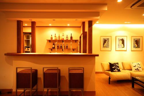 a living room with a bar with chairs and a couch at Kinosaki Yamamotoya in Toyooka