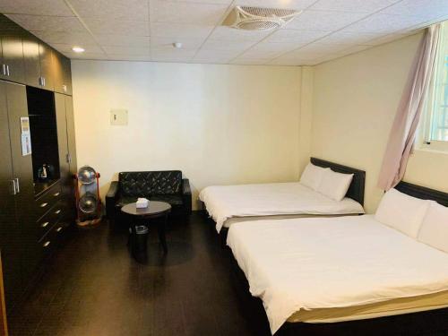 a hotel room with two beds and a chair at 金鷺民宿 in Jincheng