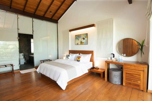 a bedroom with a bed and a desk and a mirror at River Arc in Panadura