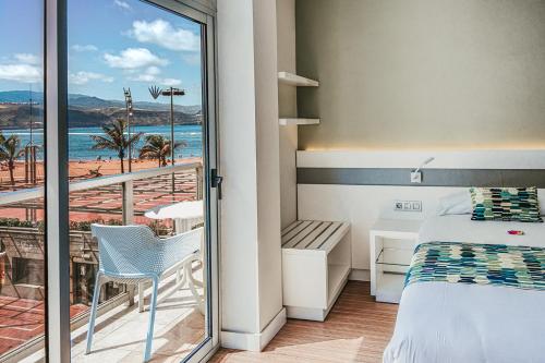 Un dormitorio con una cama y un balcón con vistas. en Hotel Aloe Canteras, en Las Palmas de Gran Canaria