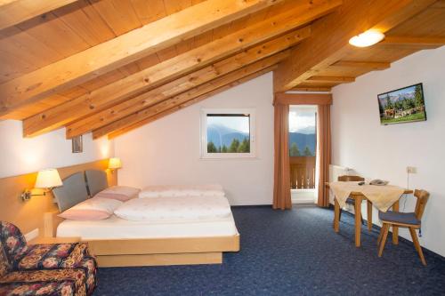 een slaapkamer met een bed en een tafel in een kamer bij Gasthof St. Ulrich in Meltina