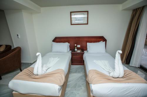 two beds in a hotel room with swanspretending to be wings at AIFU Hotel El Montazah Alexandria in Alexandria
