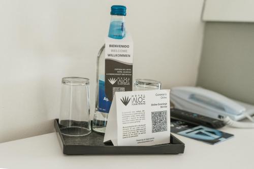 a bottle of water and two glasses on a table at Hotel Aloe Canteras in Las Palmas de Gran Canaria