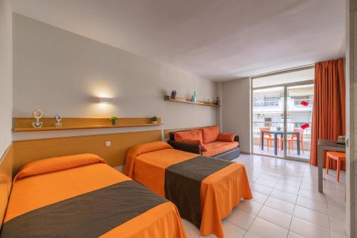 a hotel room with two beds and a chair at Apartamento bonito en Salou con piscina in Salou