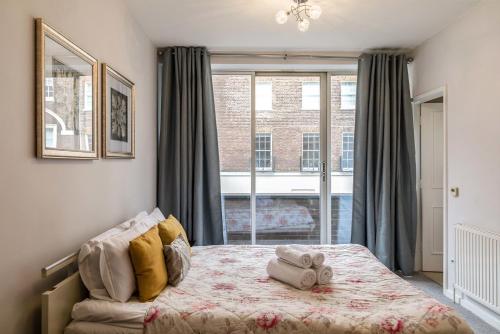 a bedroom with a bed and a large window at PickThePlace 3-bedroom Portman square in London