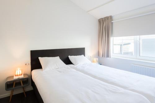 - une chambre avec un grand lit blanc et une fenêtre dans l'établissement Hello Zeeland - Vakantiehuis Beatrixstraat 29A, à Domburg