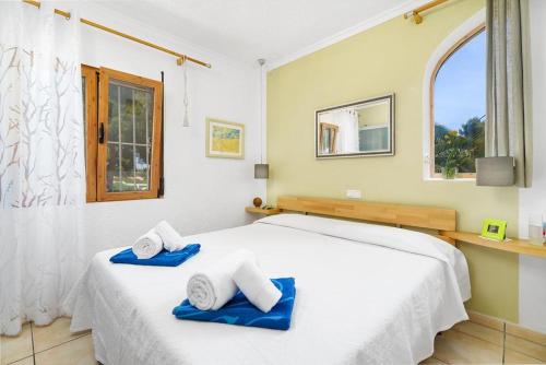 Un dormitorio con una cama blanca con toallas azules. en Puravida, en Jávea