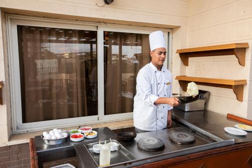 a chef standing in a kitchen preparing food at AIFU Hotel El Montazah Alexandria in Alexandria