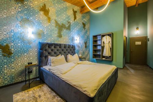 a bedroom with a large bed with a blue wall at Pensiunea Casa Buna in Gîrbova