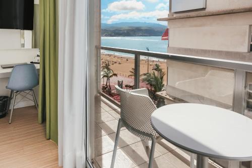a balcony with a table and chairs and a view of the beach at Hotel Aloe Canteras in Las Palmas de Gran Canaria