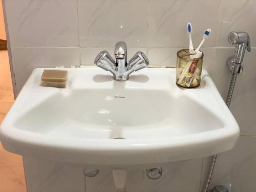 a white sink with toothbrushes in a bathroom at Metro Nook in Lucknow