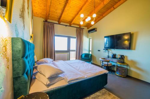 a bedroom with a bed and a desk and a television at Pensiunea Casa Buna in Gîrbova