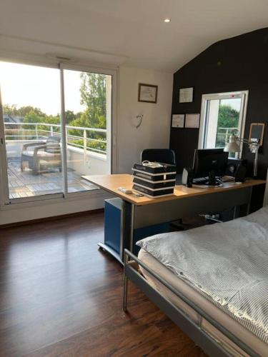 a bedroom with a desk and a bed and a balcony at Chambres au calme chez l'habitant in Vertou