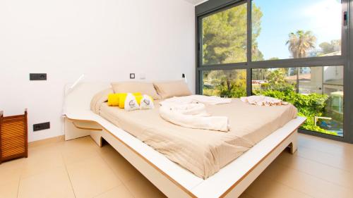 Bett in einem Zimmer mit einem großen Fenster in der Unterkunft Villa PAM Beach house Playa de Muro - 200m to beach in Alcúdia