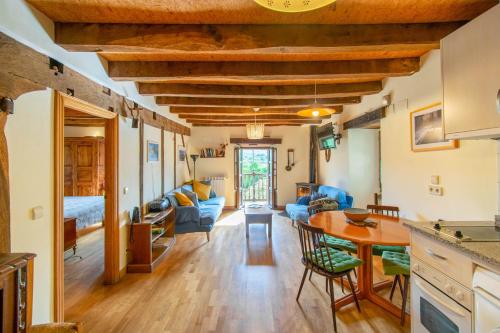 a kitchen and living room with a wooden ceiling at Casa Monaut, acogedores apartamentos a los pies de la selva de Irati in Saragüeta